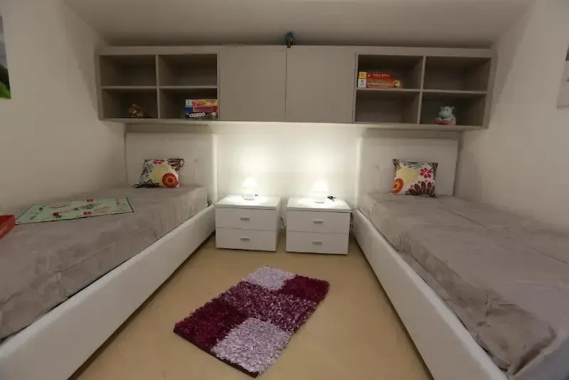 Twin bedroom with modern decor and storage shelves in a Sicilian holiday home
