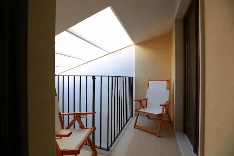 Cozy indoor sitting area with wicker sofa and balcony access in a Sicilian holiday home