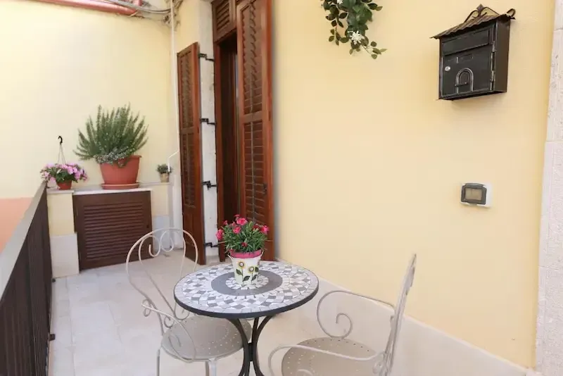 Sunny Sicilian patio with mosaic table, flowers and cozy outdoor seating