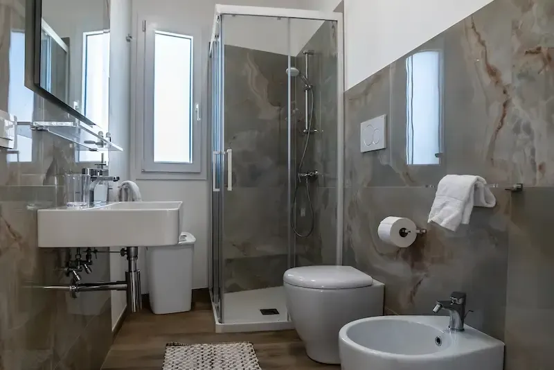 Villa Stella Polares modern bathroom with shower, toilet, sink, and gray marble-style walls