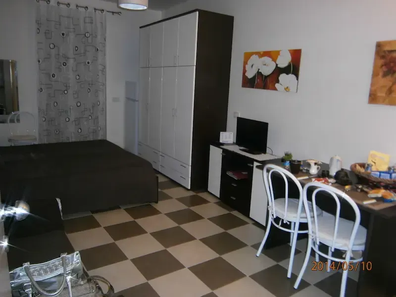 Small bedroom with a bed, wardrobe, desk, computer, and checkered tile floor