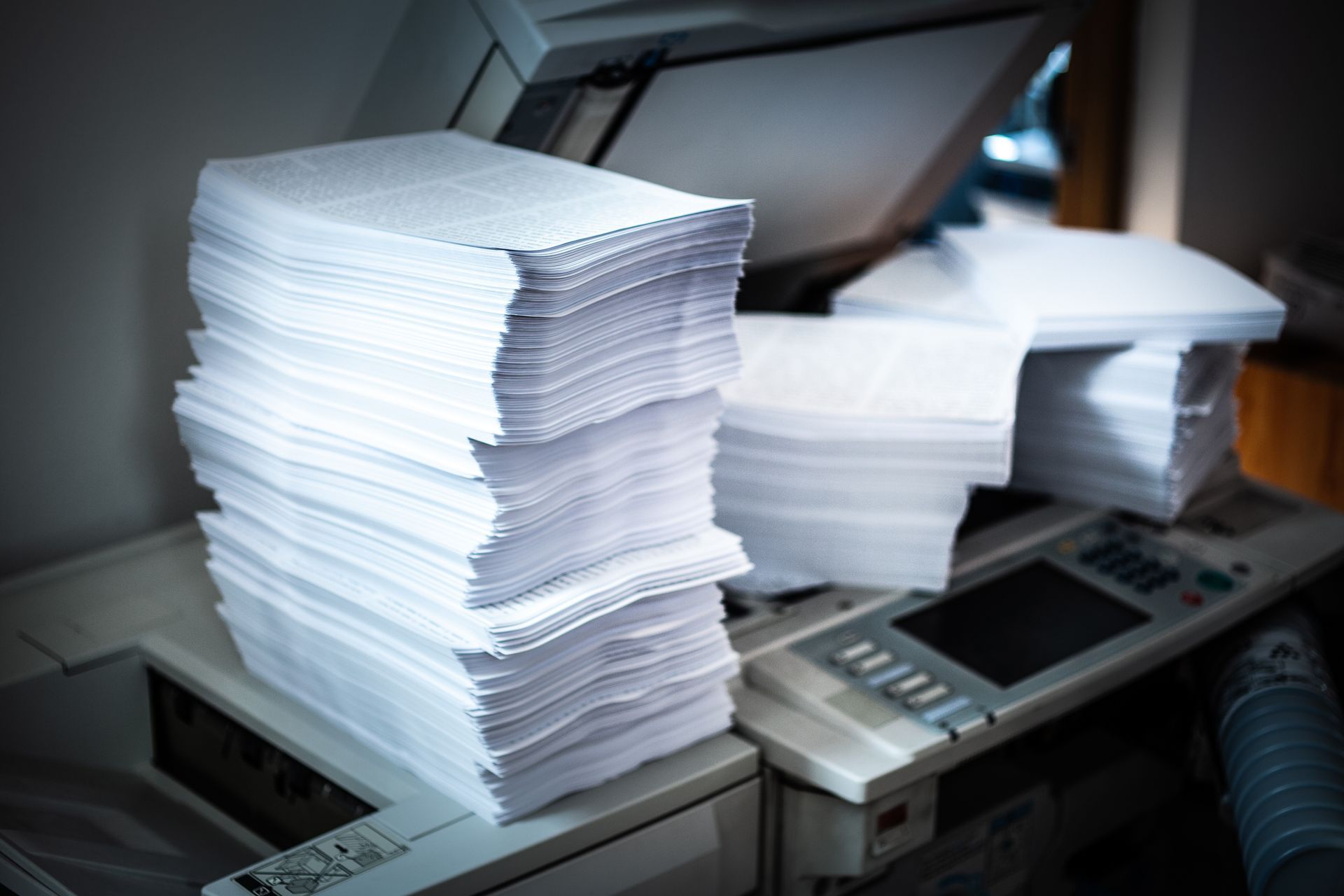 Stacks of white paper on a copier or printer in an office setting