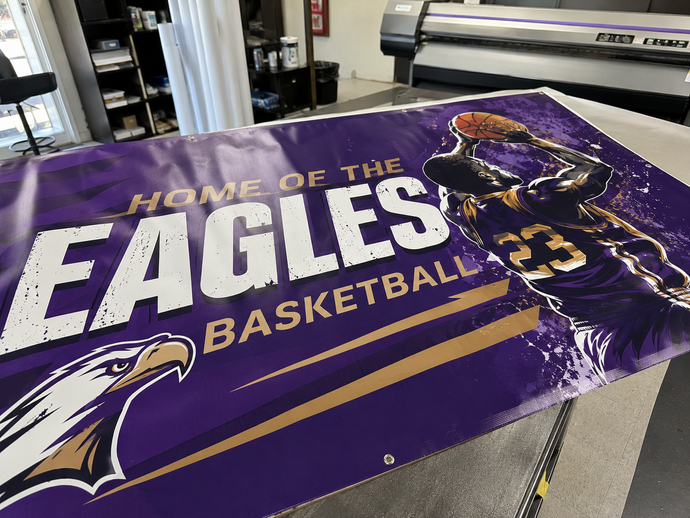 Purple “Home of the Eagles Basketball” banner with a basketball player graphic on a table
