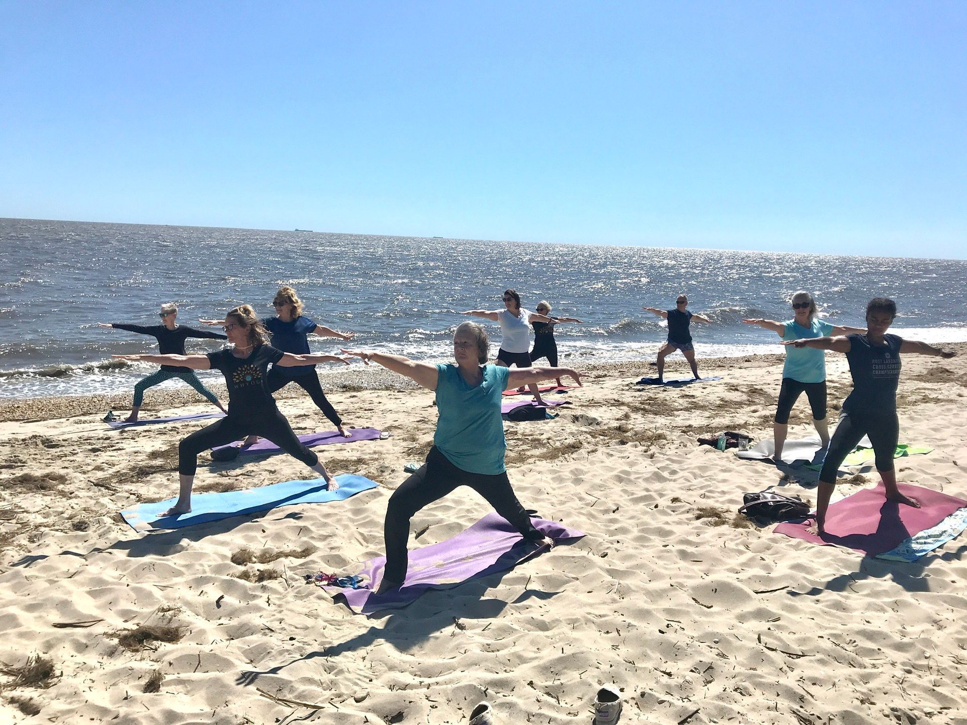 A group of people are doing yoga on the beach.