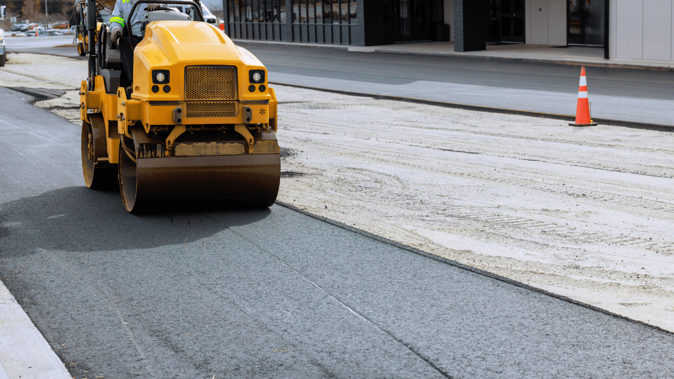 Yellow road roller compacting a freshly prepared base layer before asphalt installation on a city street during an asphalt paving service in Centennial, CO
