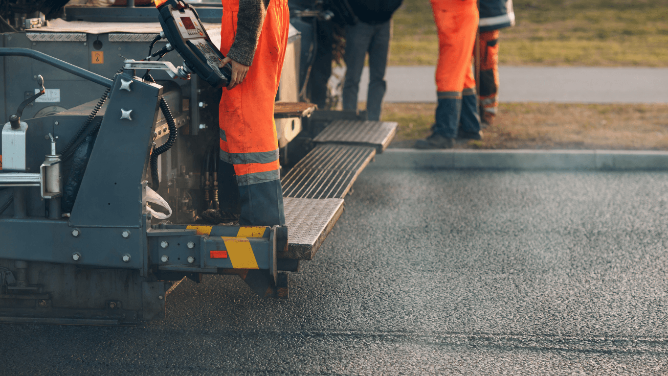 Smooth black asphalt road curving through a green landscape with trees and distant mountains during an asphalt paving service in Centennial, CO