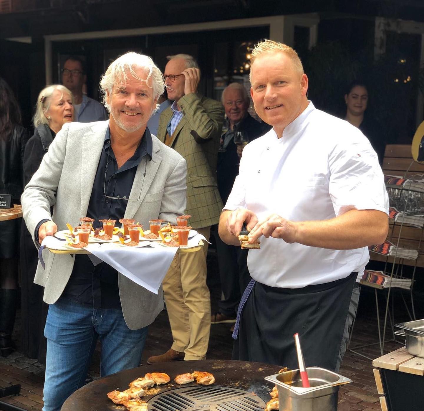 Twee mannen staan โโnaast elkaar met dienbladen vol eten