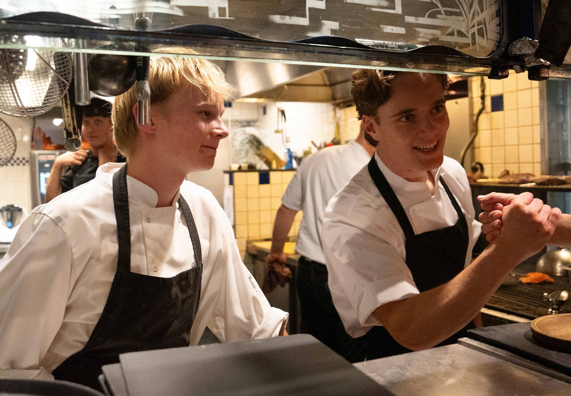 Twee mannen in schorten staan โโnaast elkaar in een keuken
