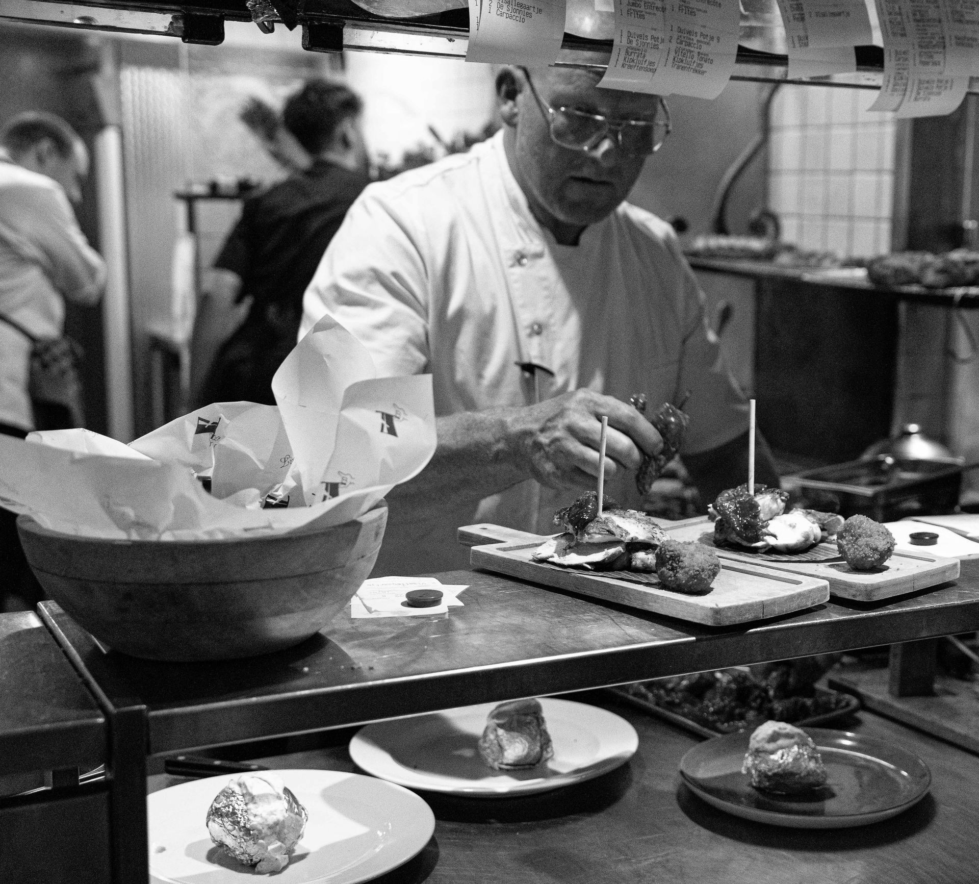 Een zwart-witfoto van een chef-kok die eten bereidt