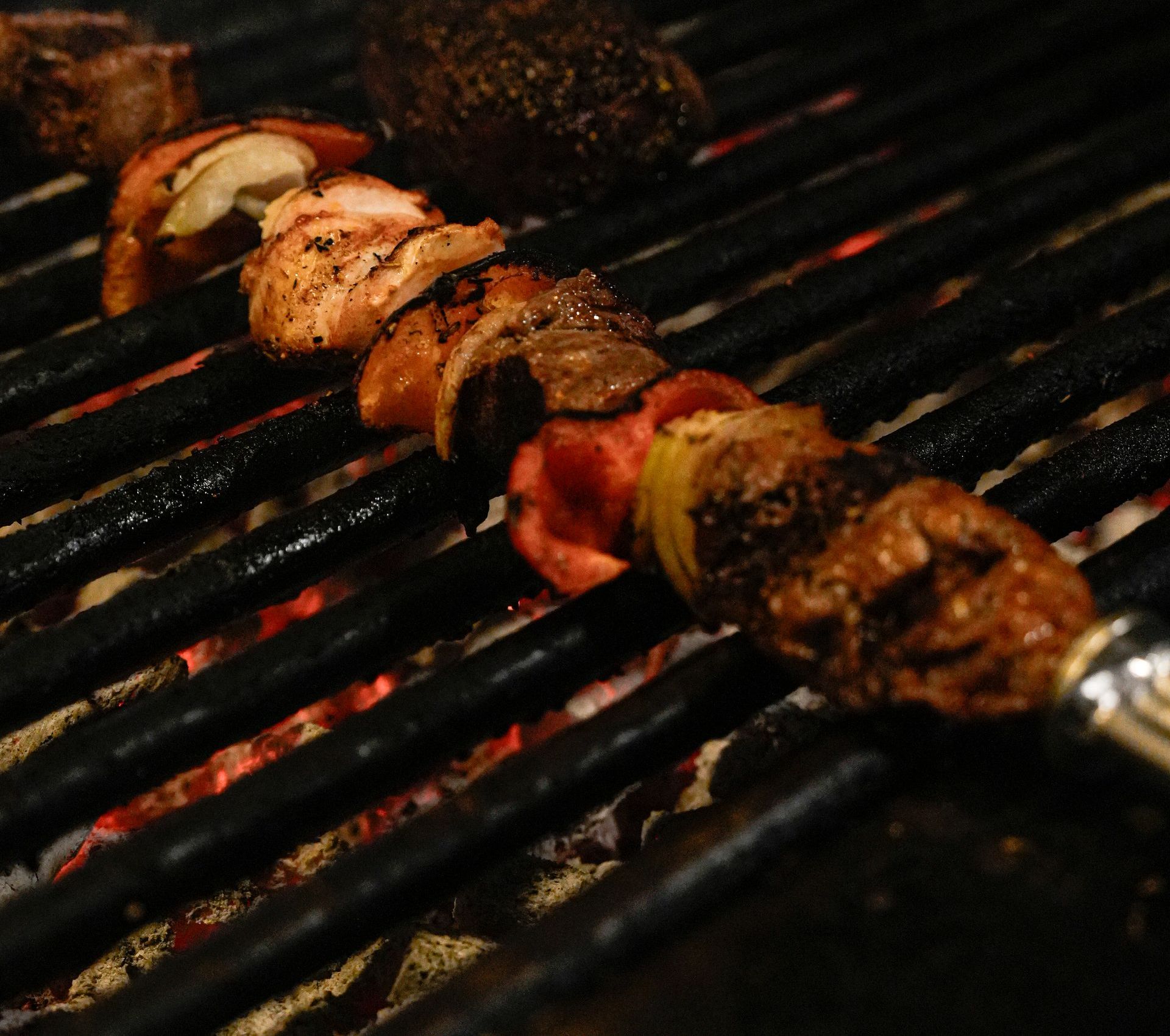 Een spiesje vlees wordt op een grill gekookt. Bij Linke Loetje