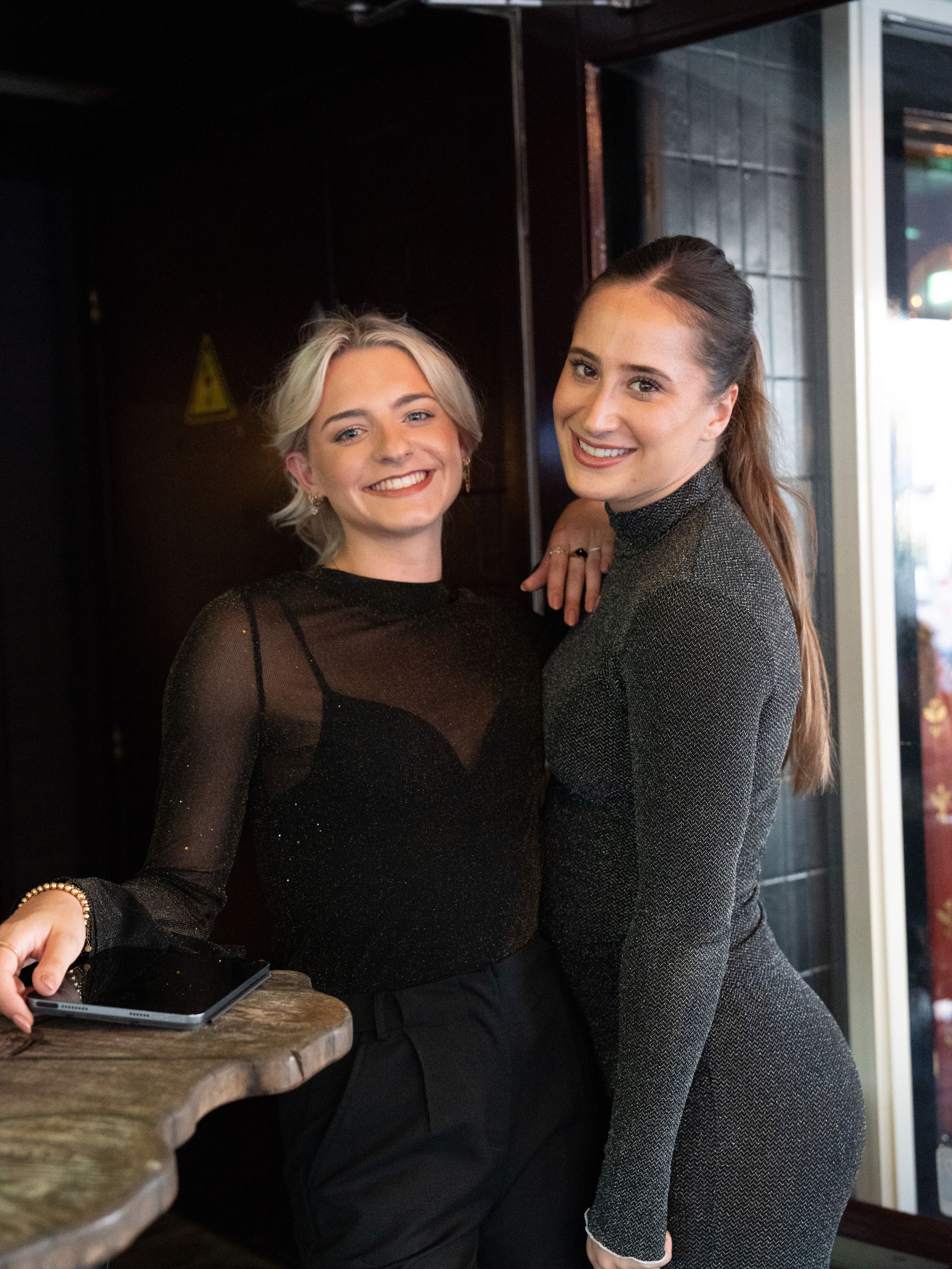 Twee vrouwen poseren samen voor een foto in een restaurant.