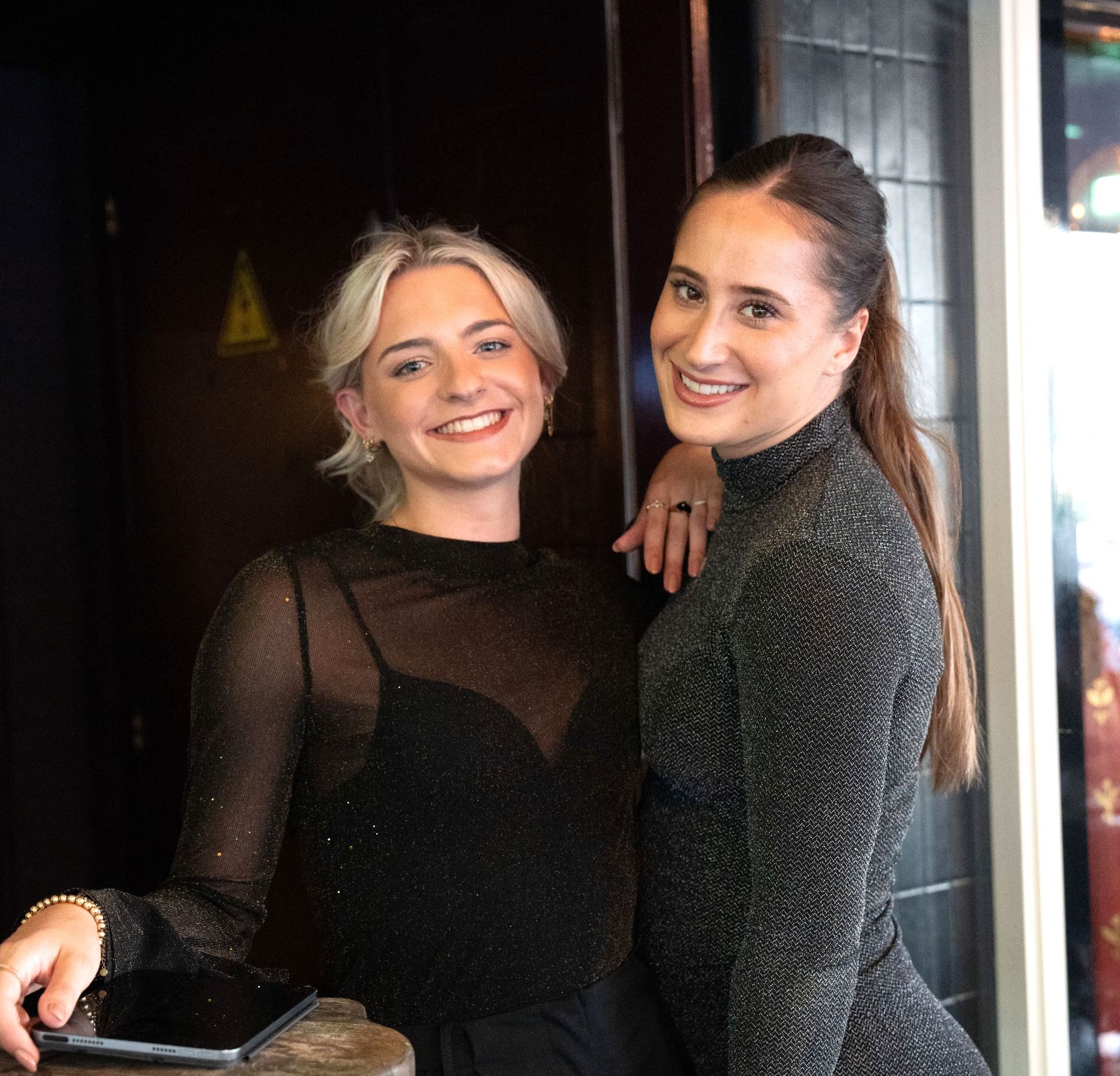 Twee vrouwen poseren voor een foto en รฉรฉn houdt een tablet vast