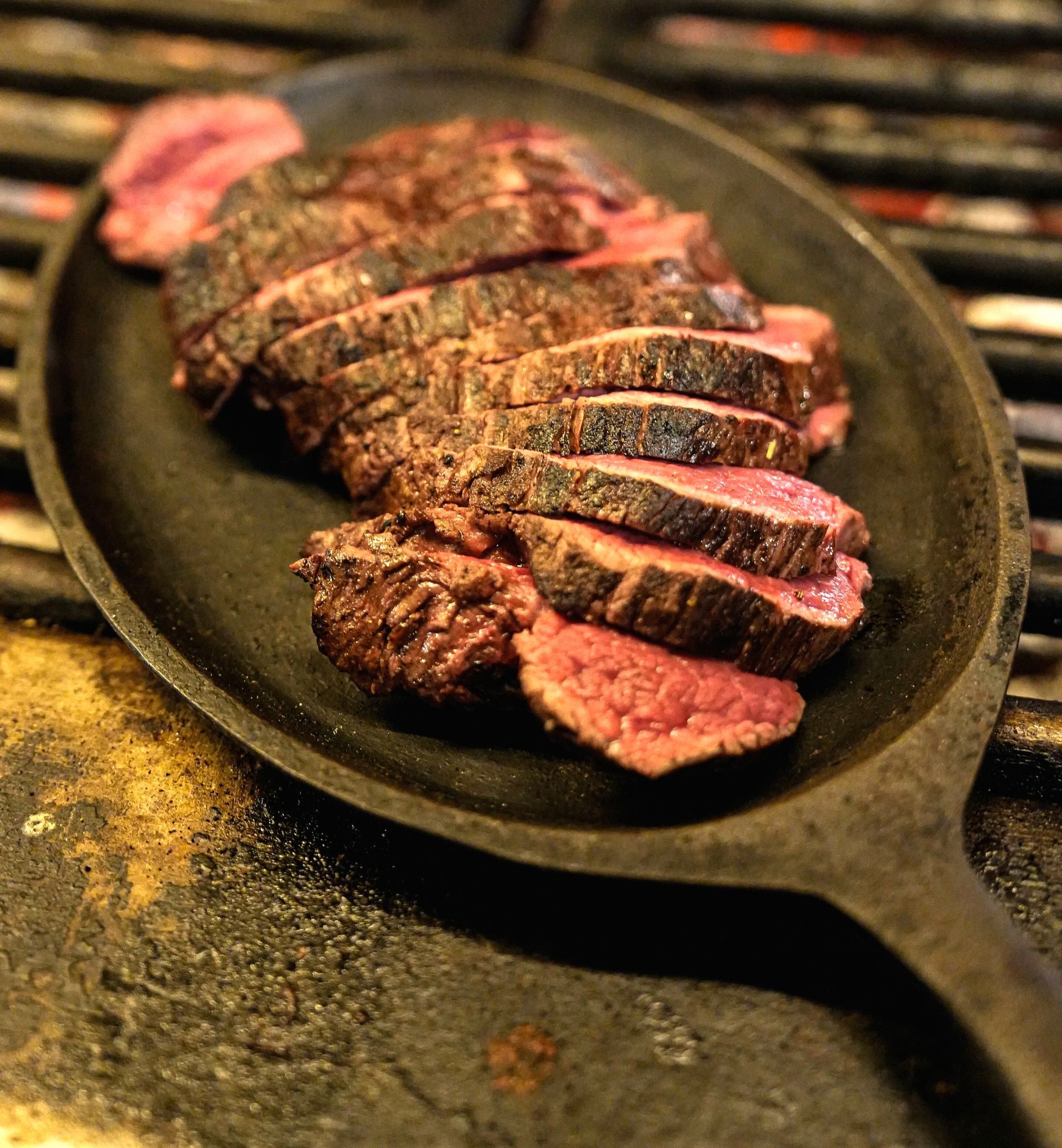Een koekenpan gevuld met plakjes biefstuk op een grill bij Linke Loetje