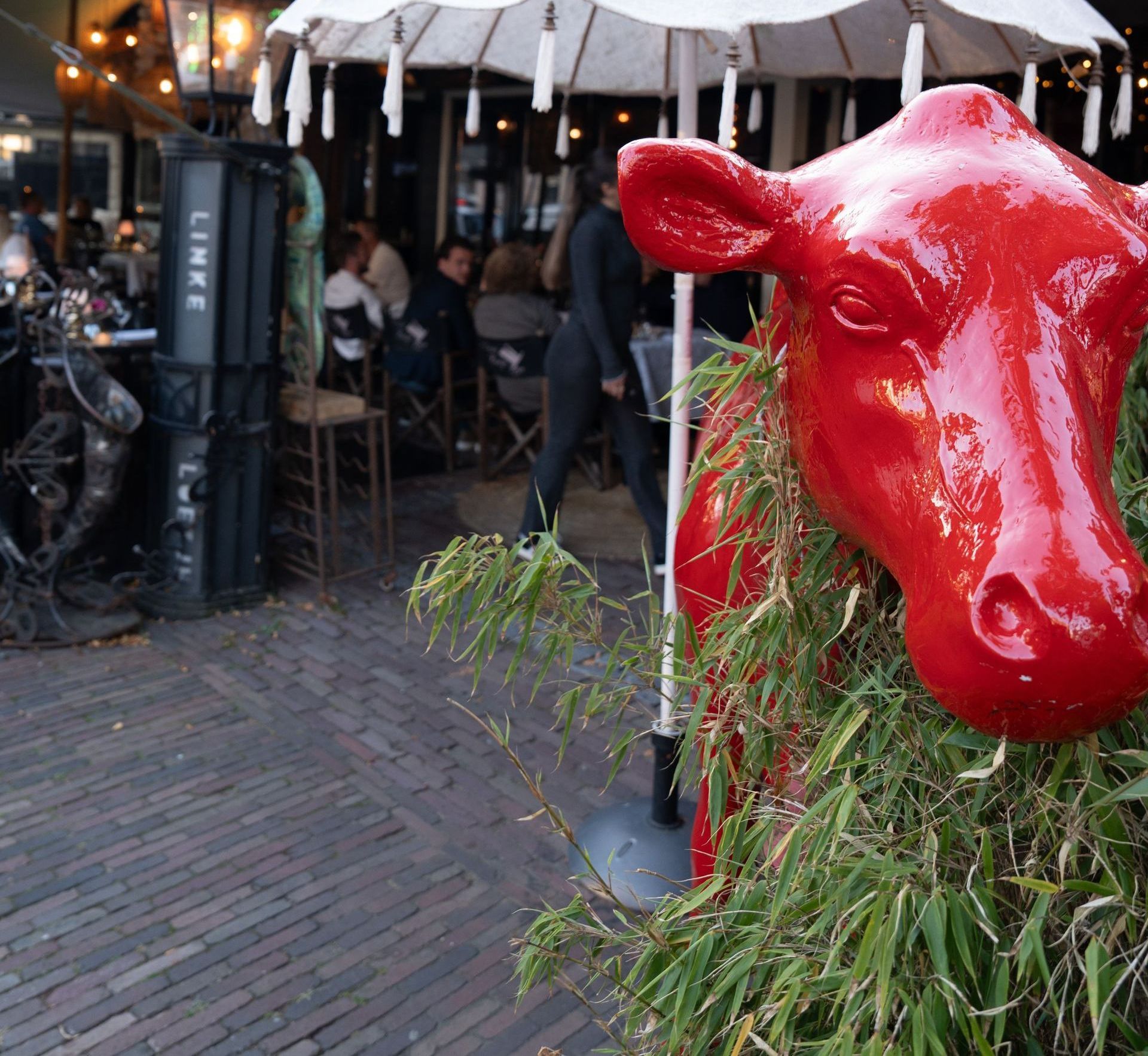 Een standbeeld van een rode koe staat voor een restaurant
