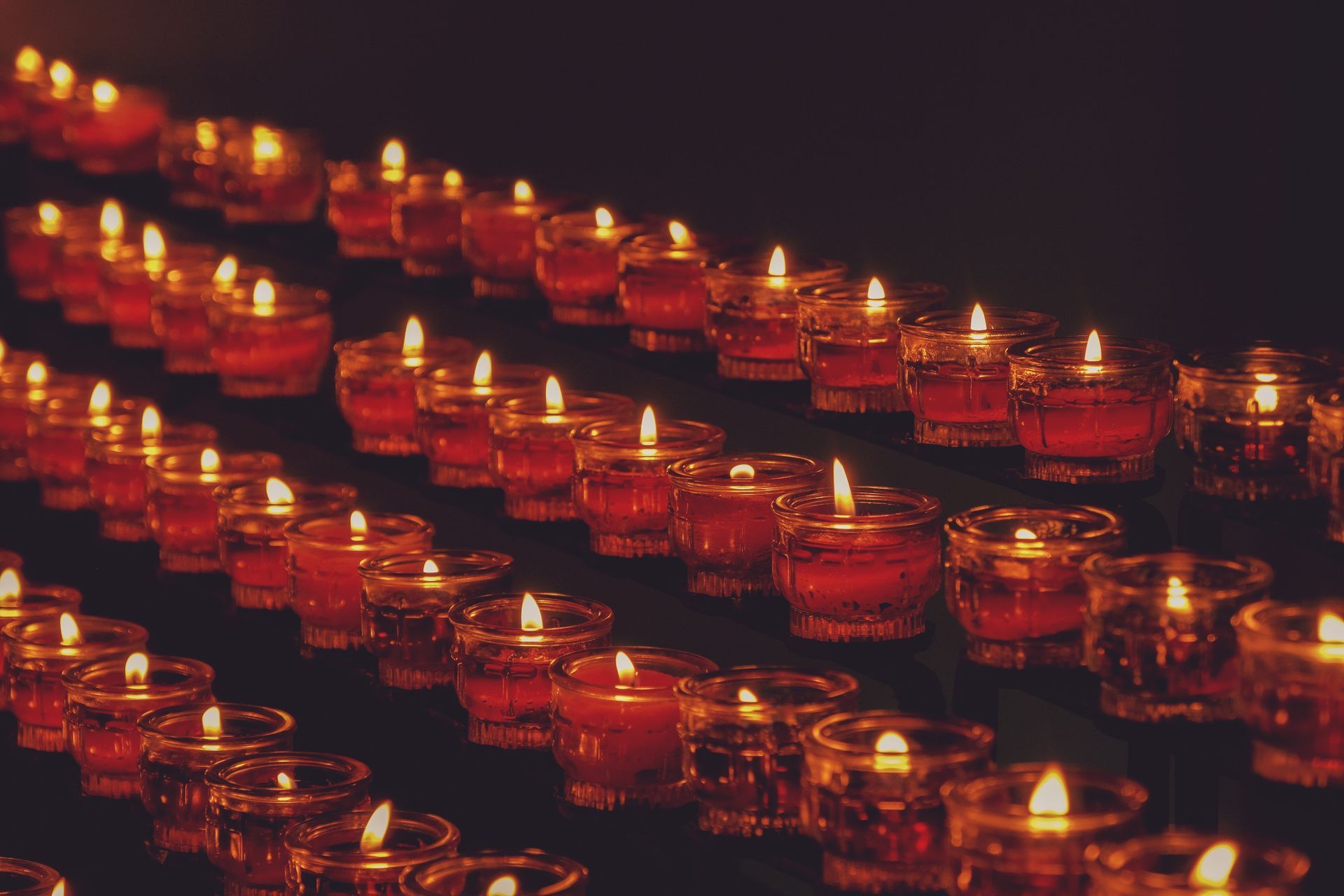 Rows of glowing red candles in a dark setting, creating a warm, festive light