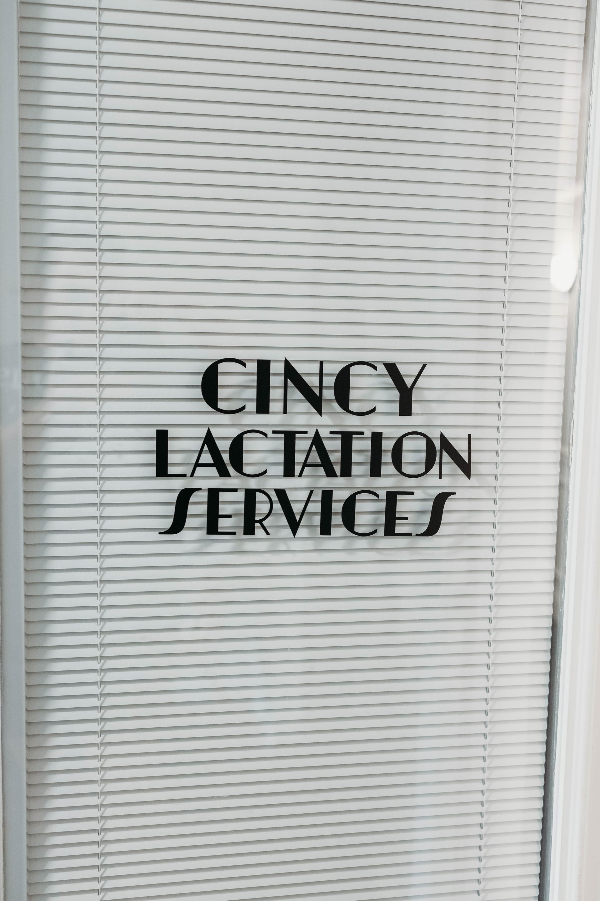 Cincy Lactation Services sign on a glass door with blinds in the background.