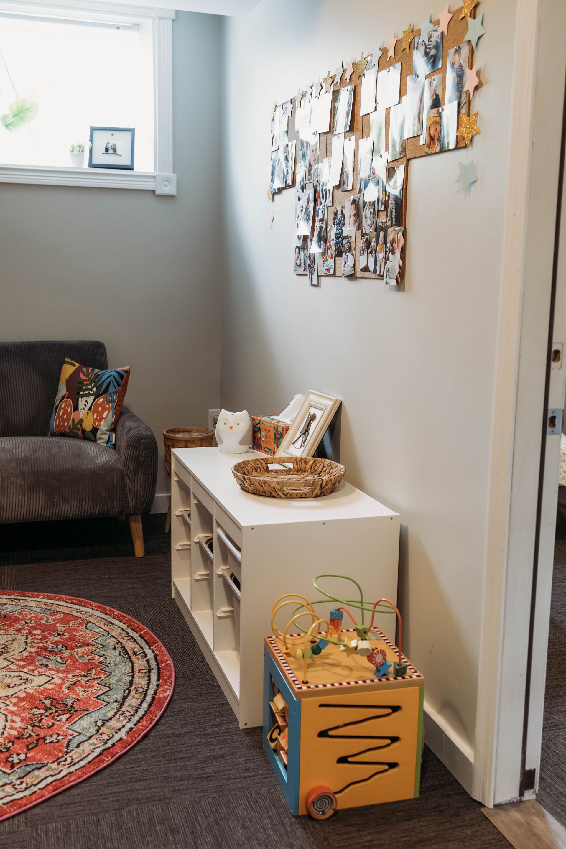 Cozy room with gray walls, sofa, colorful rug, white storage cabinet, and wooden toy.
