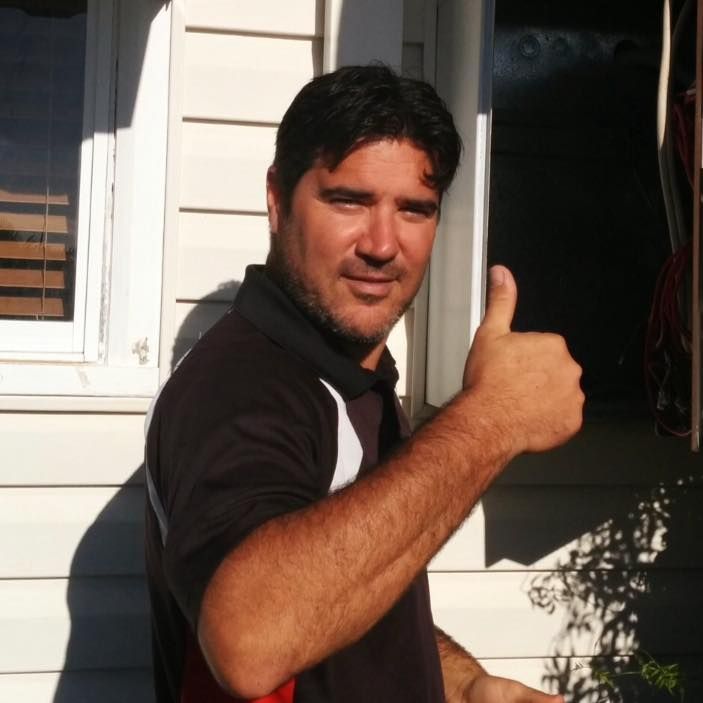 Man with dark hair and a beard gives a thumbs-up outside a building — Robert Coony Electrician in Nambucca Heads, NSW