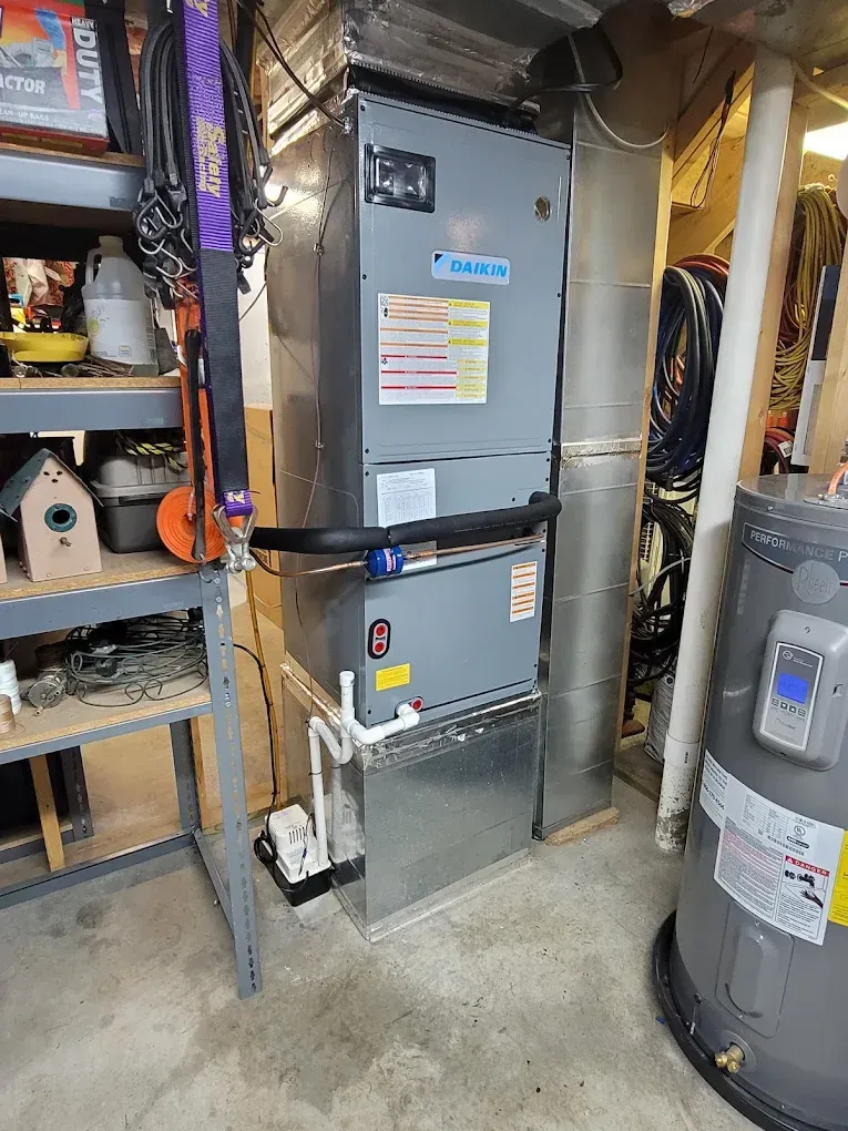 Furnace and water heater in a cluttered basement utility area with shelves and exposed ductwork