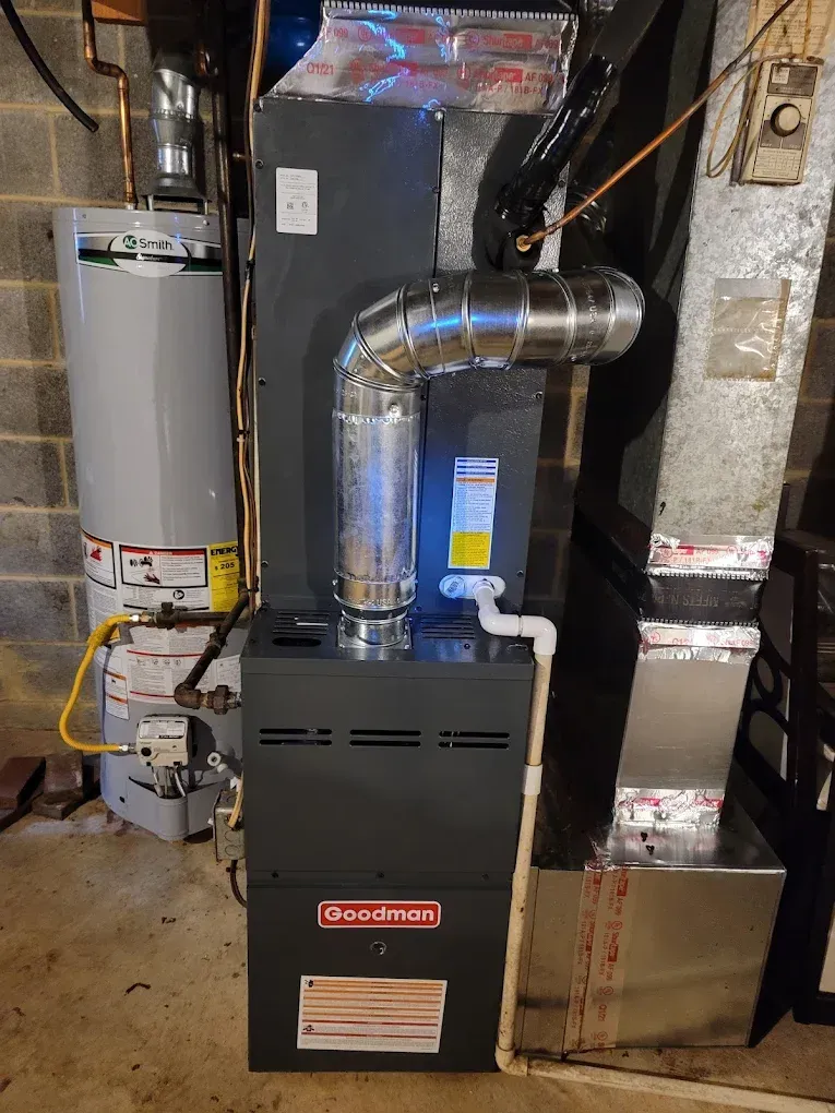 Basement HVAC furnace with ductwork and water heater in a utility room