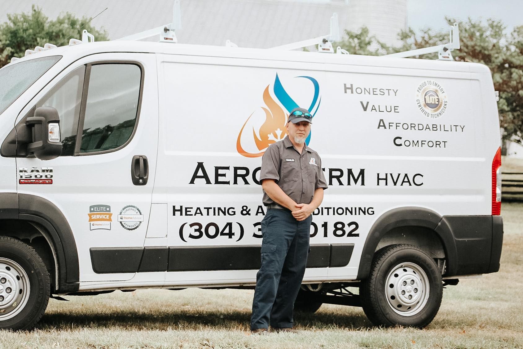 HVAC service van with a worker standing beside it in front of a white fence