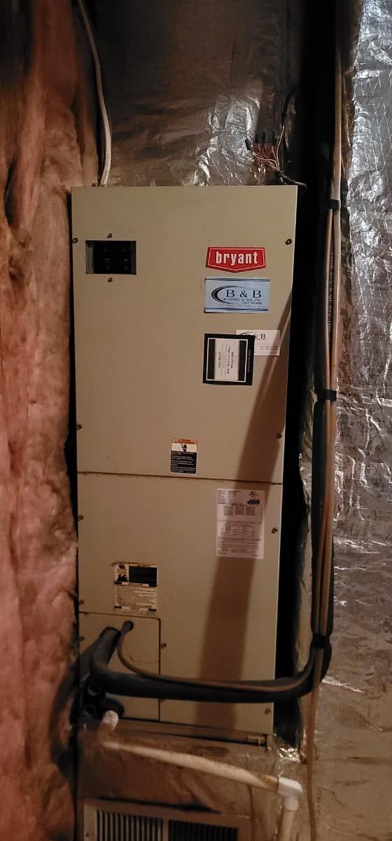 Beige electrical breaker panel mounted on an insulated wall with exposed wiring and black conduit