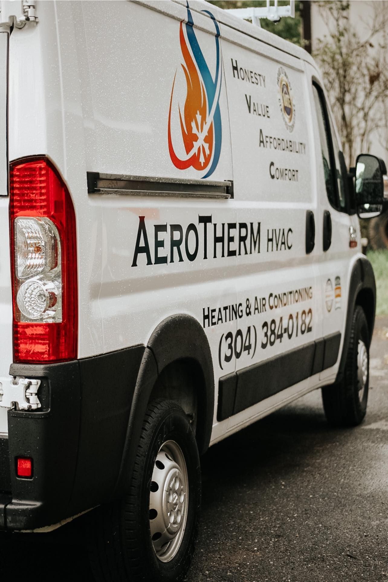White Aerotherm van with company logo and Russian text parked on a wet street