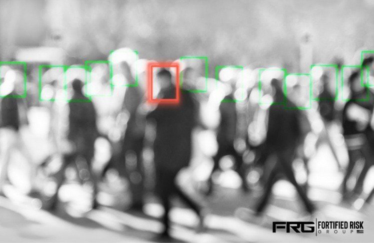 Crowd of people, grayscale, green boxes identifying faces, red box highlights one person.