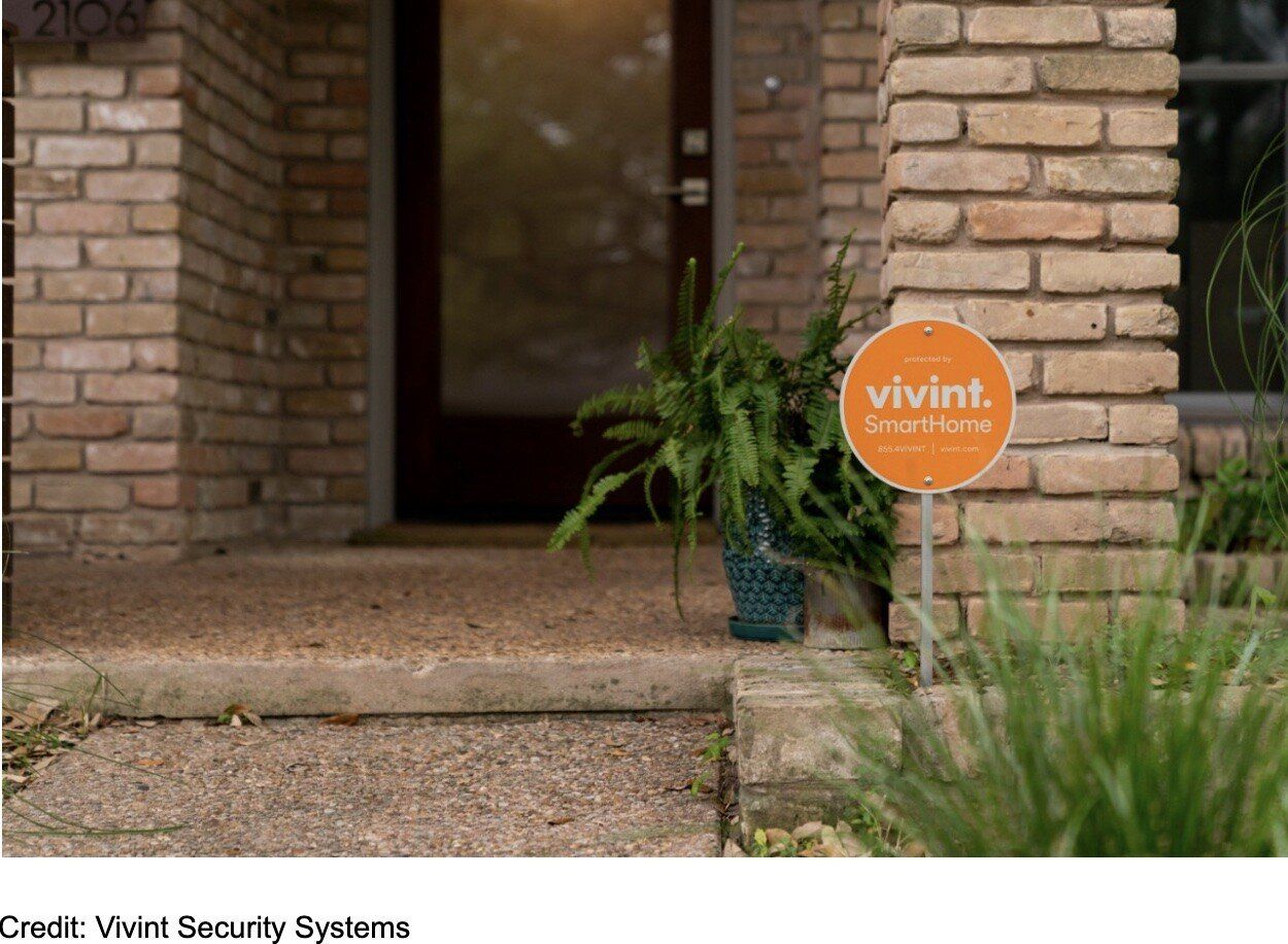Orange Vivint security sign near a home's front door and brick columns.