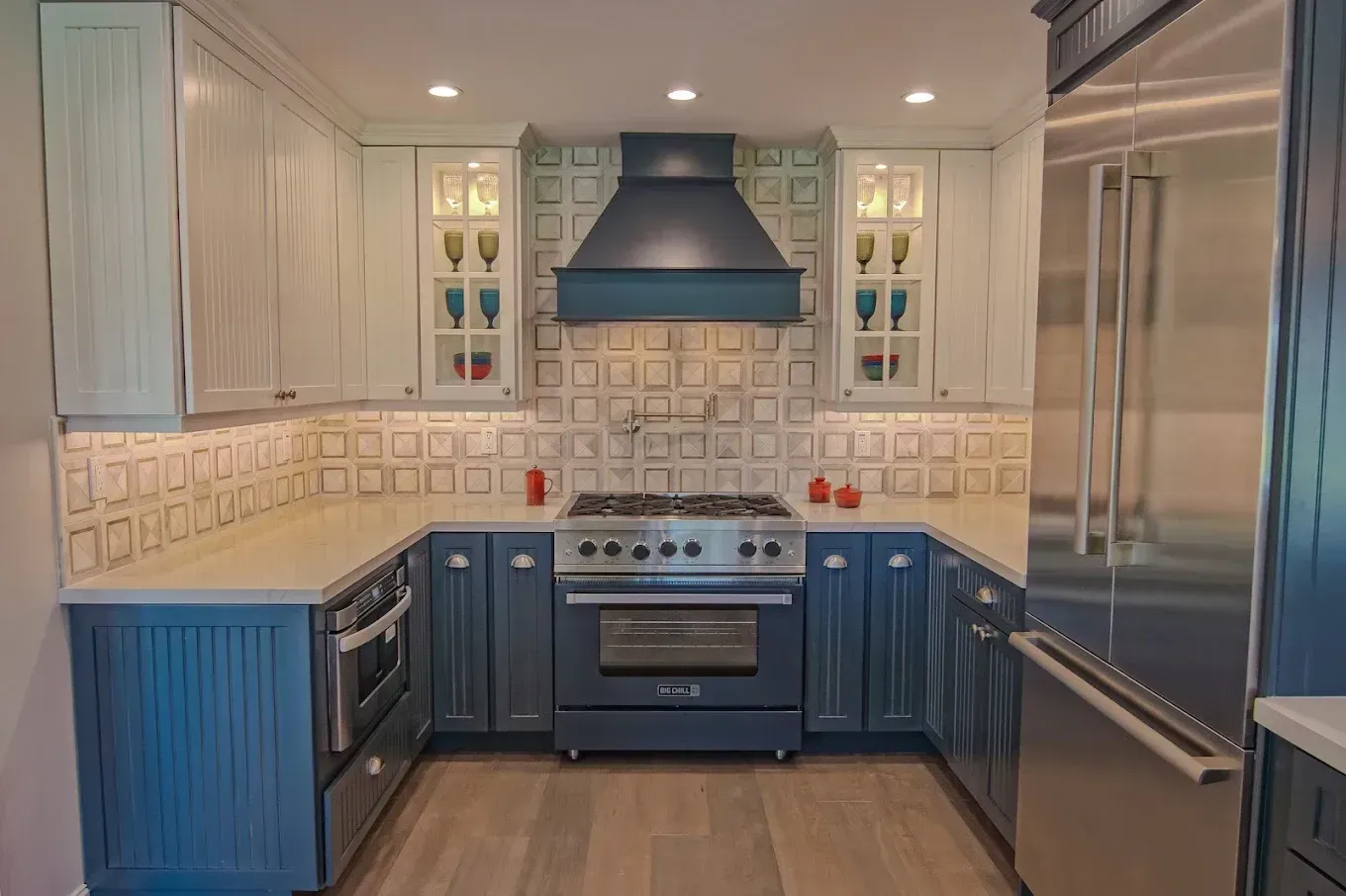 Blue and white kitchen with stainless steel appliances and a large range hood