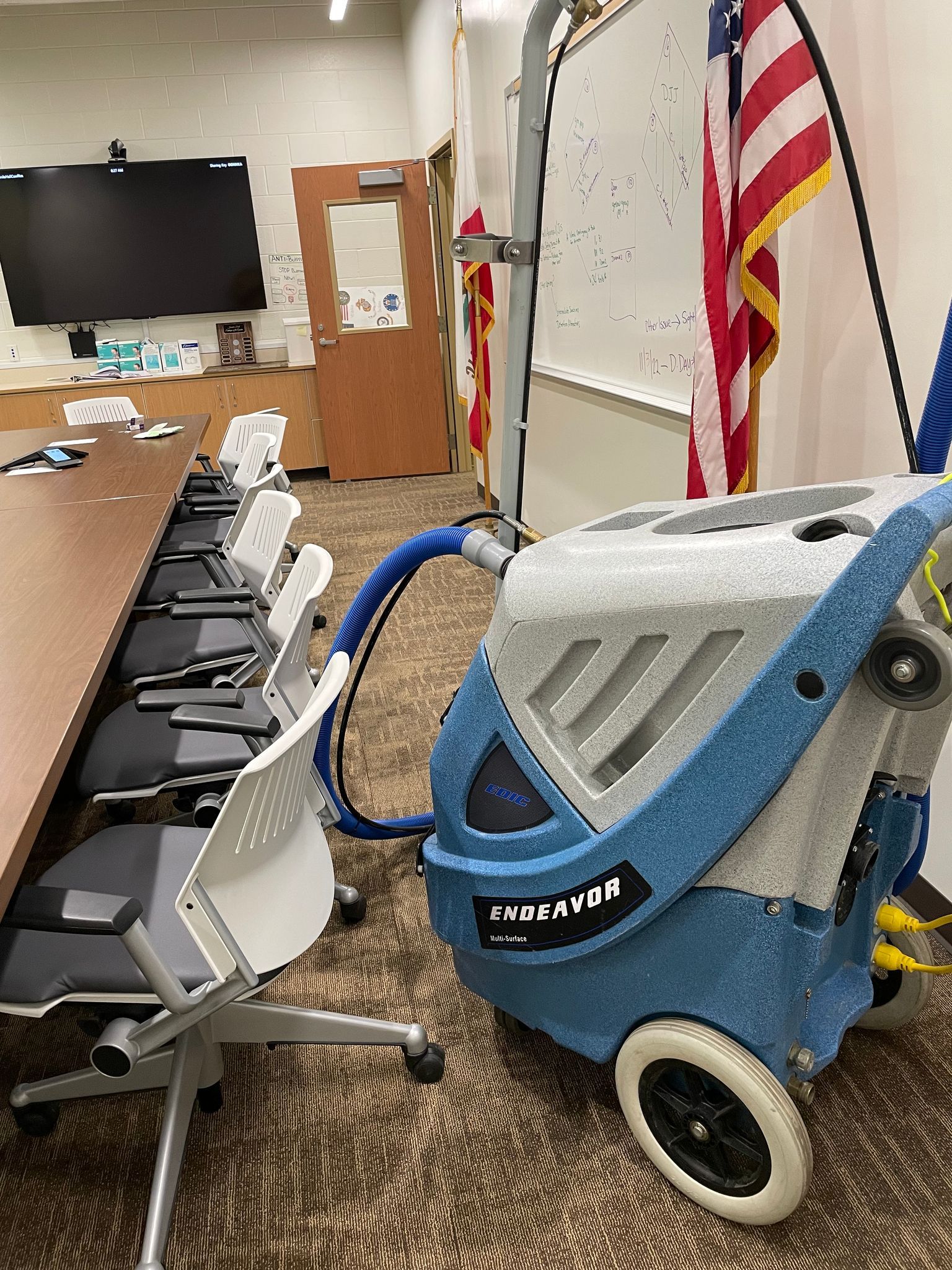 A vacuum cleaner is sitting in a conference room next to a row of chairs.