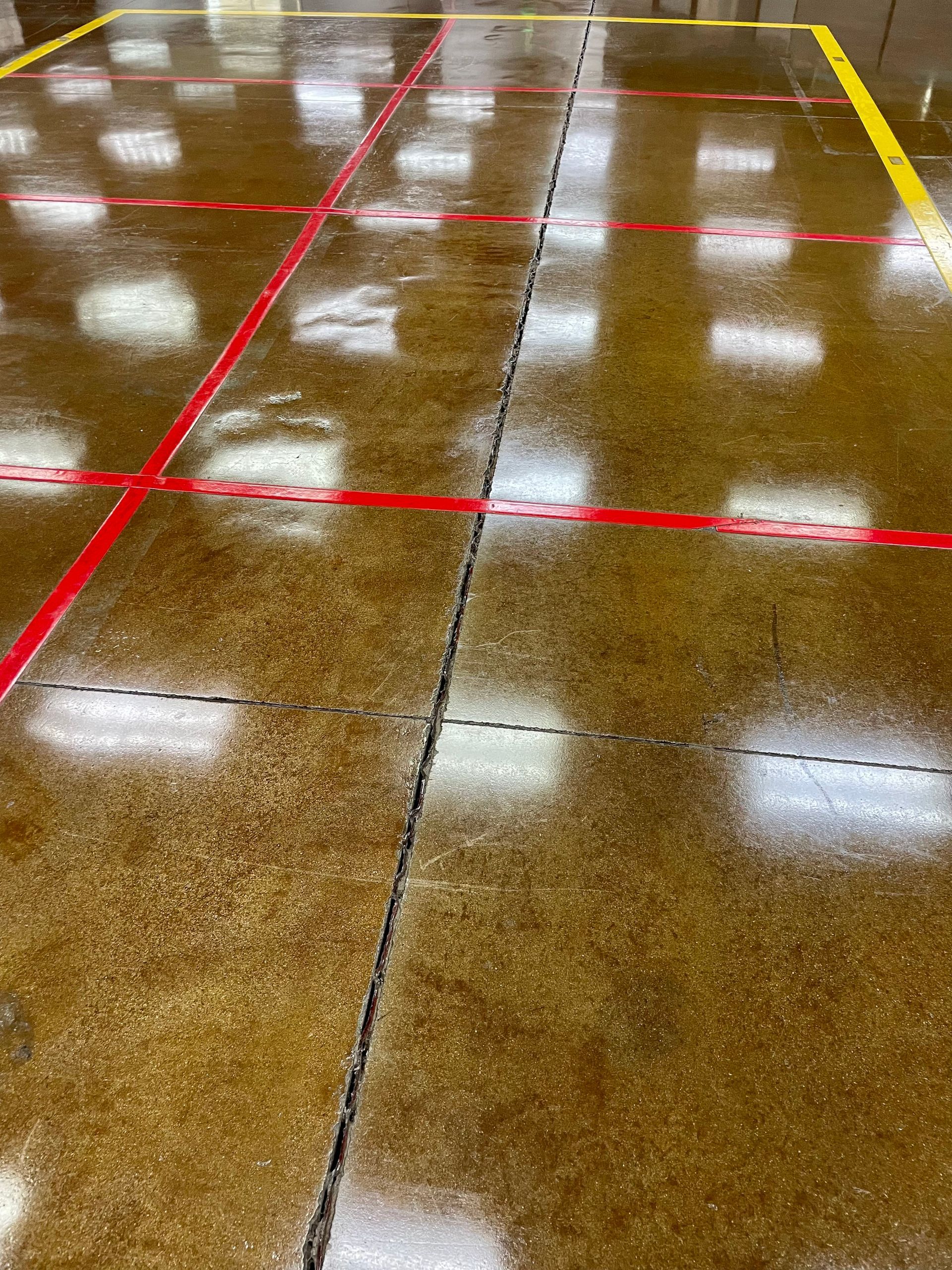 A person in a blue jacket walking in a large room with industrial floor cleaning equipment and machines.