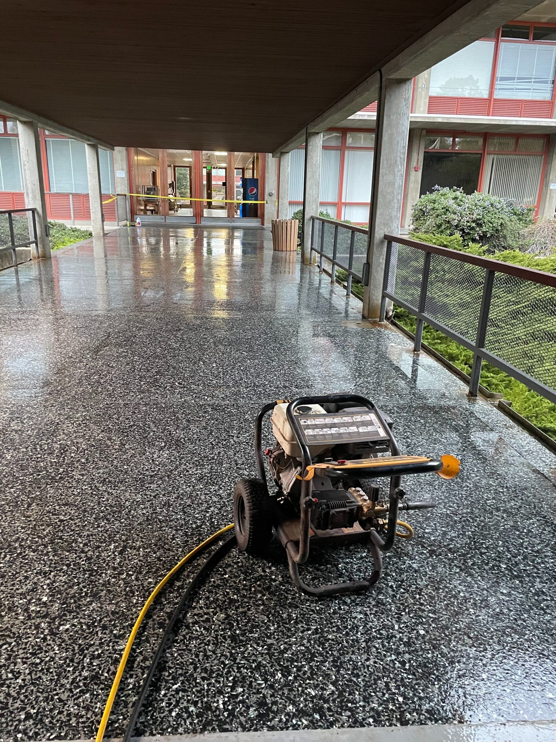 A generator is sitting on a wet floor under a bridge.