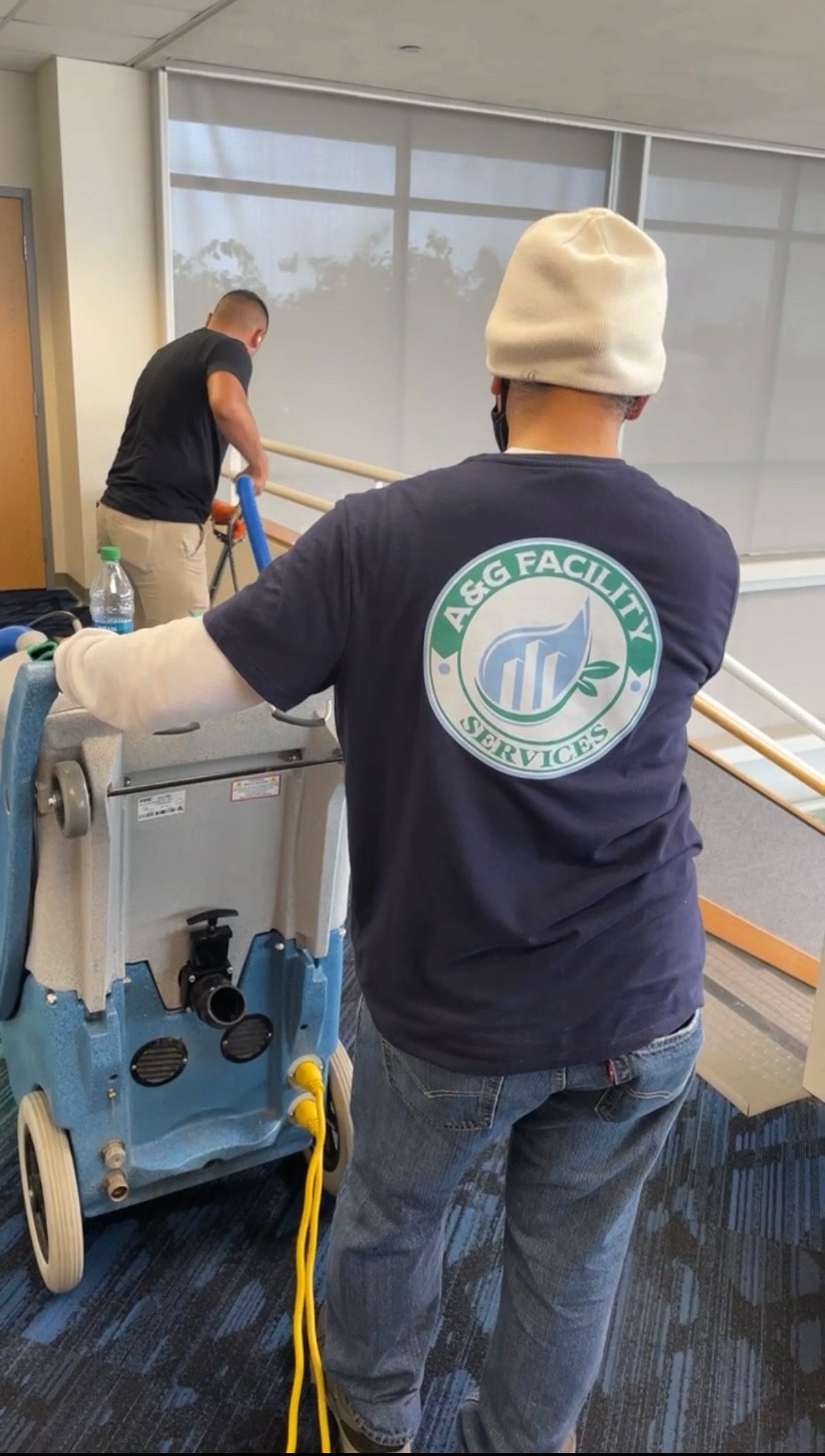 A man in a blue shirt is cleaning a room with a vacuum cleaner.