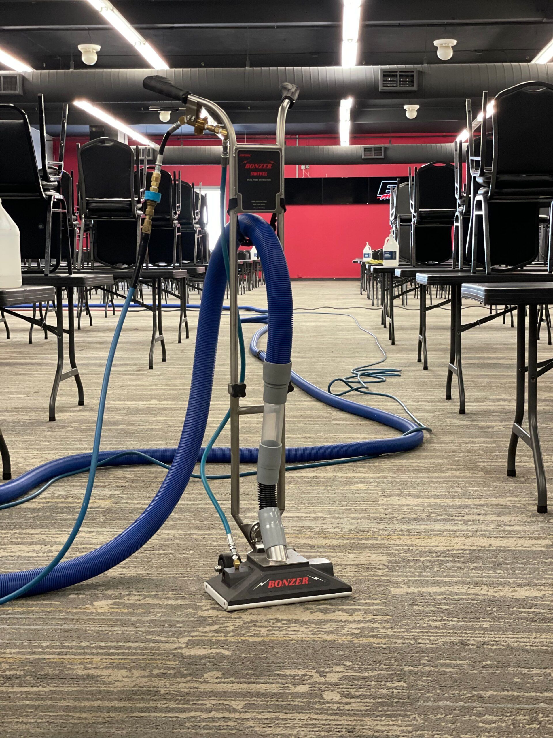 A vacuum cleaner is sitting in a conference room next to a row of chairs.
