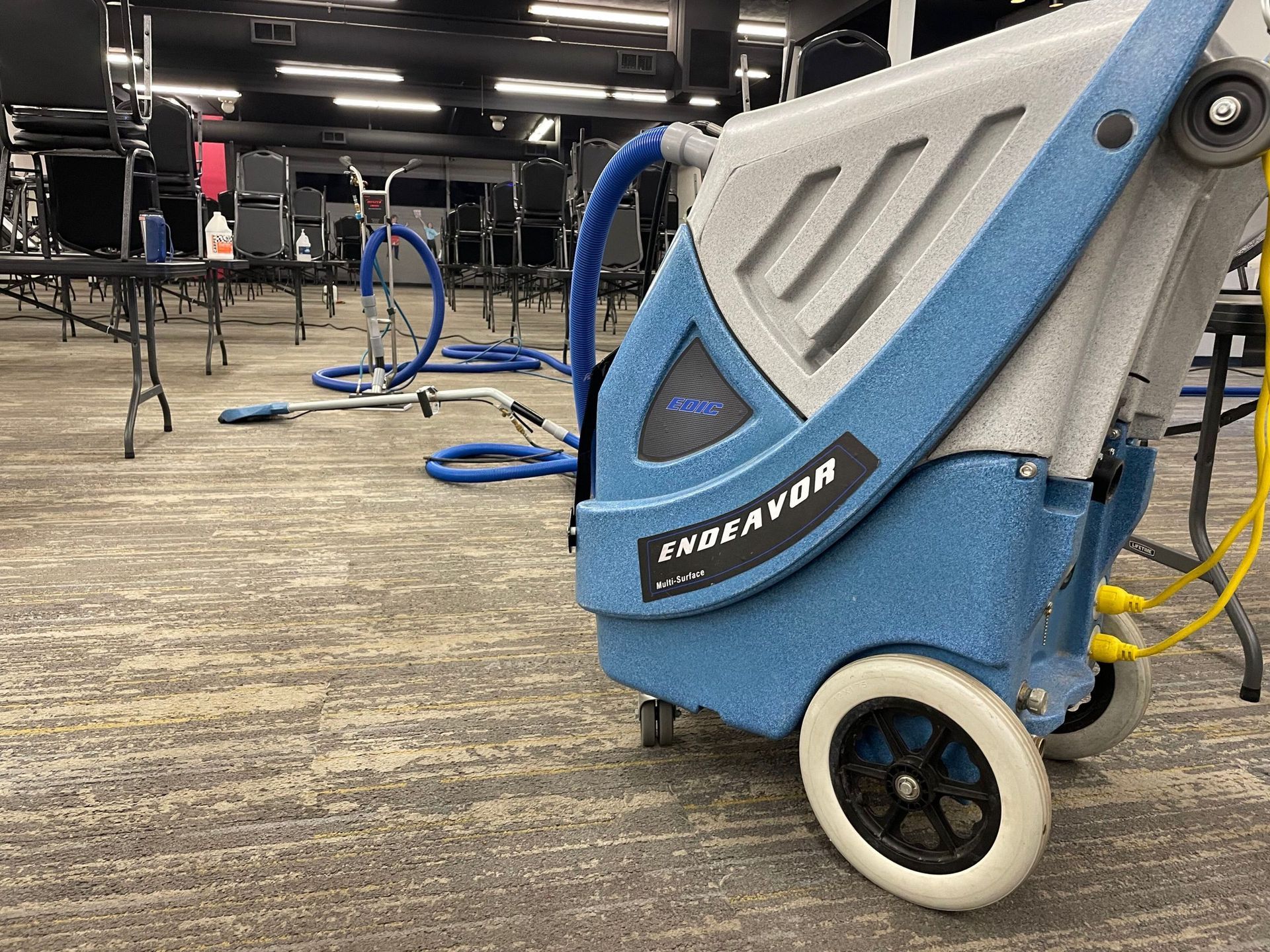 A vacuum cleaner is sitting in a conference room next to a row of chairs.