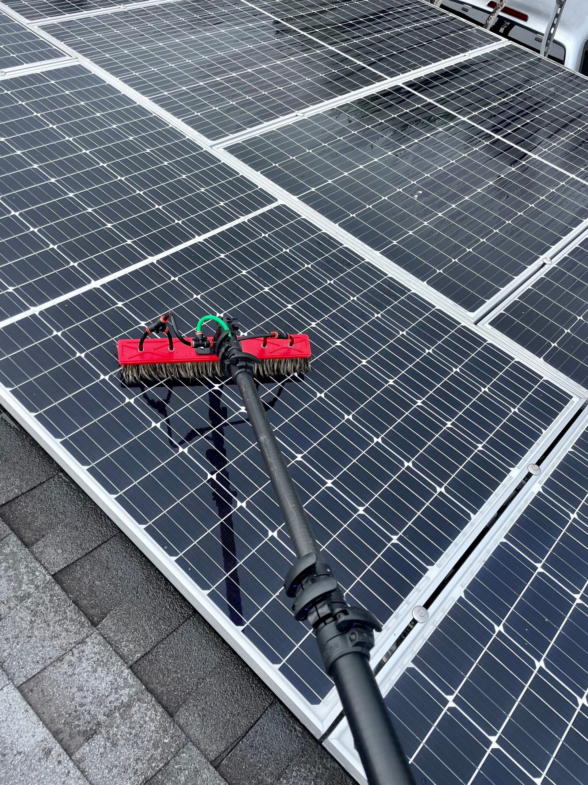 A person is cleaning a solar panel with a brush.
