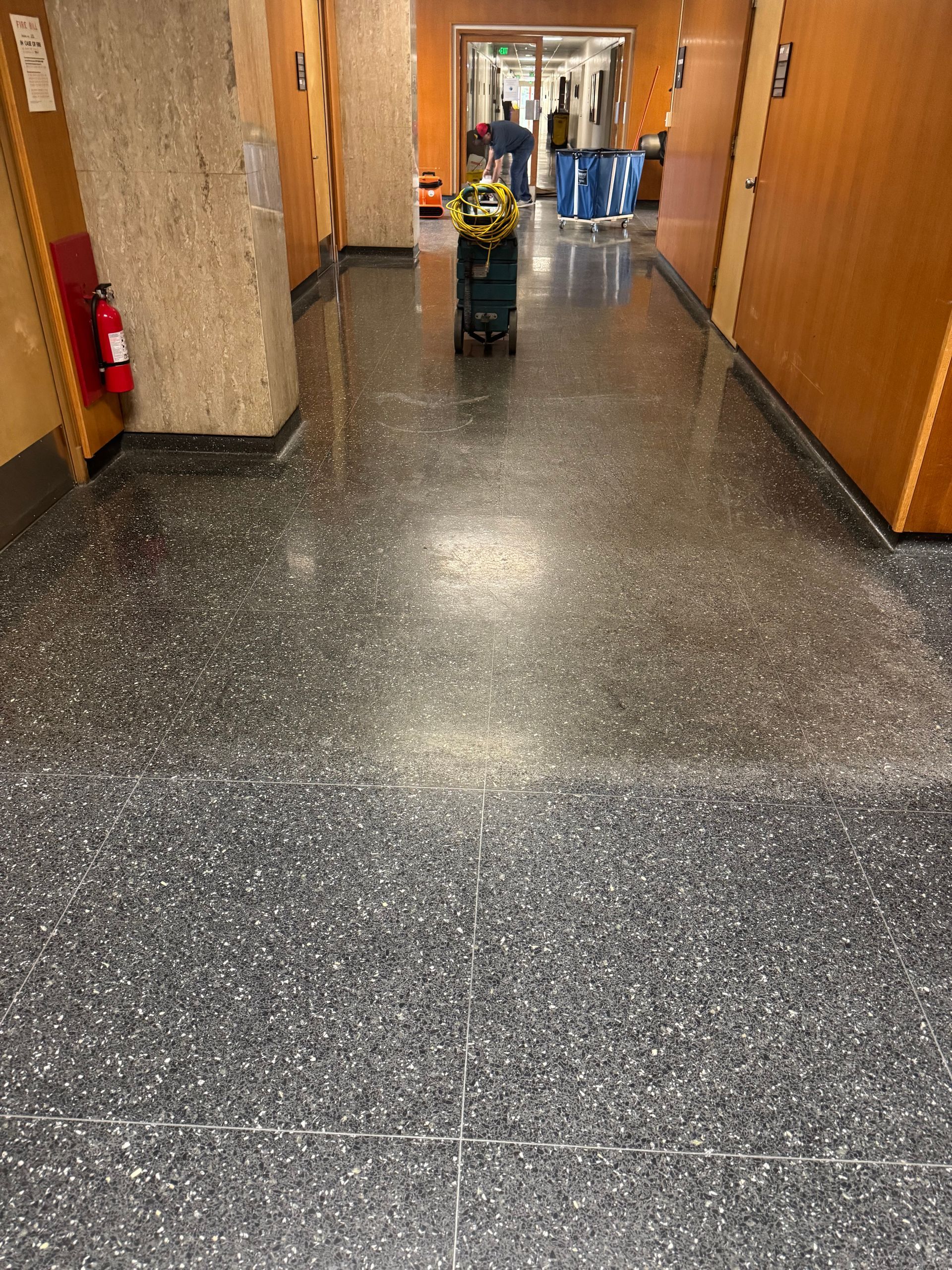 Hallway with a dark speckled floor, a cleaning machine, and doors.