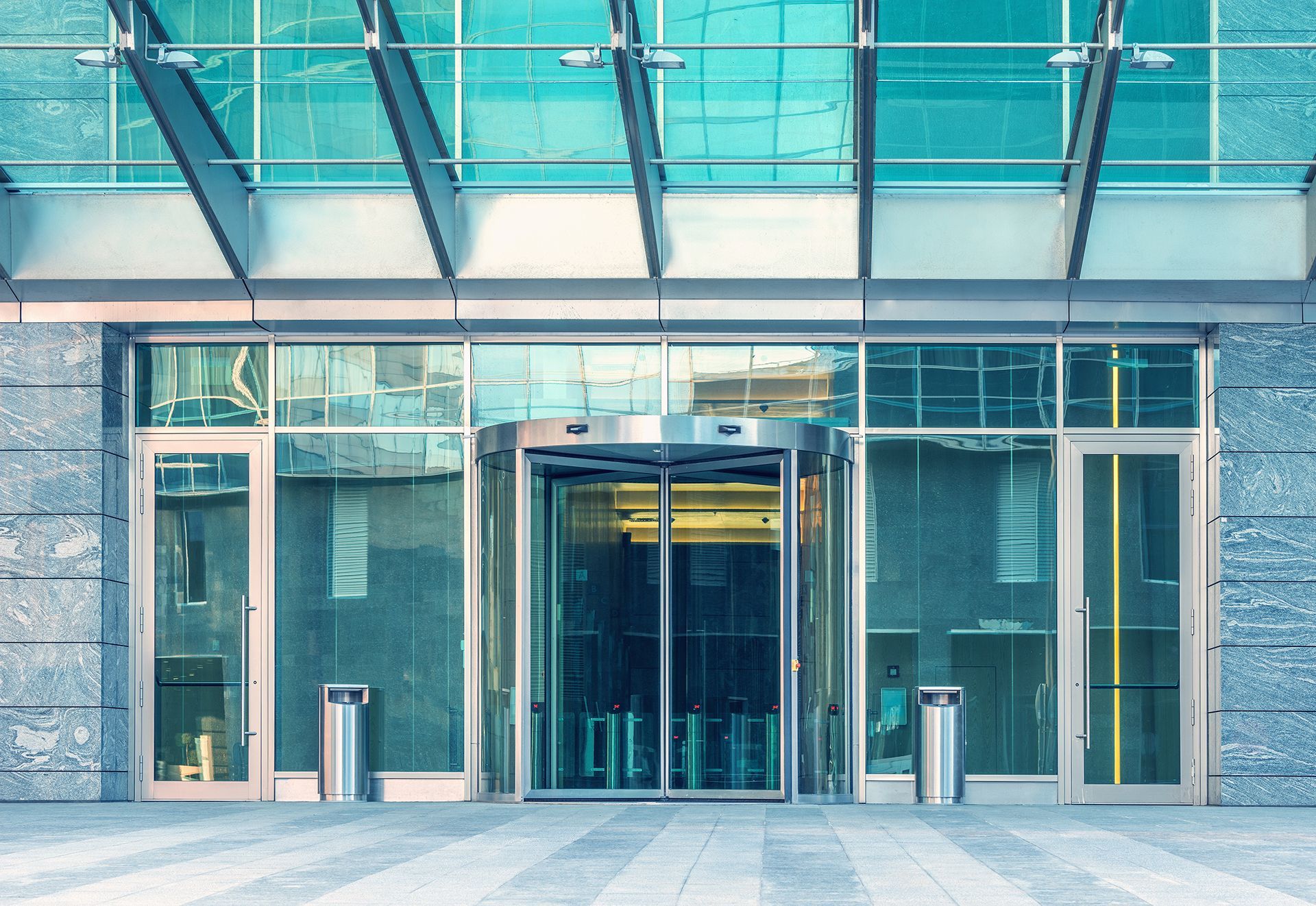 The entrance to a large building with a glass roof and sliding glass doors.