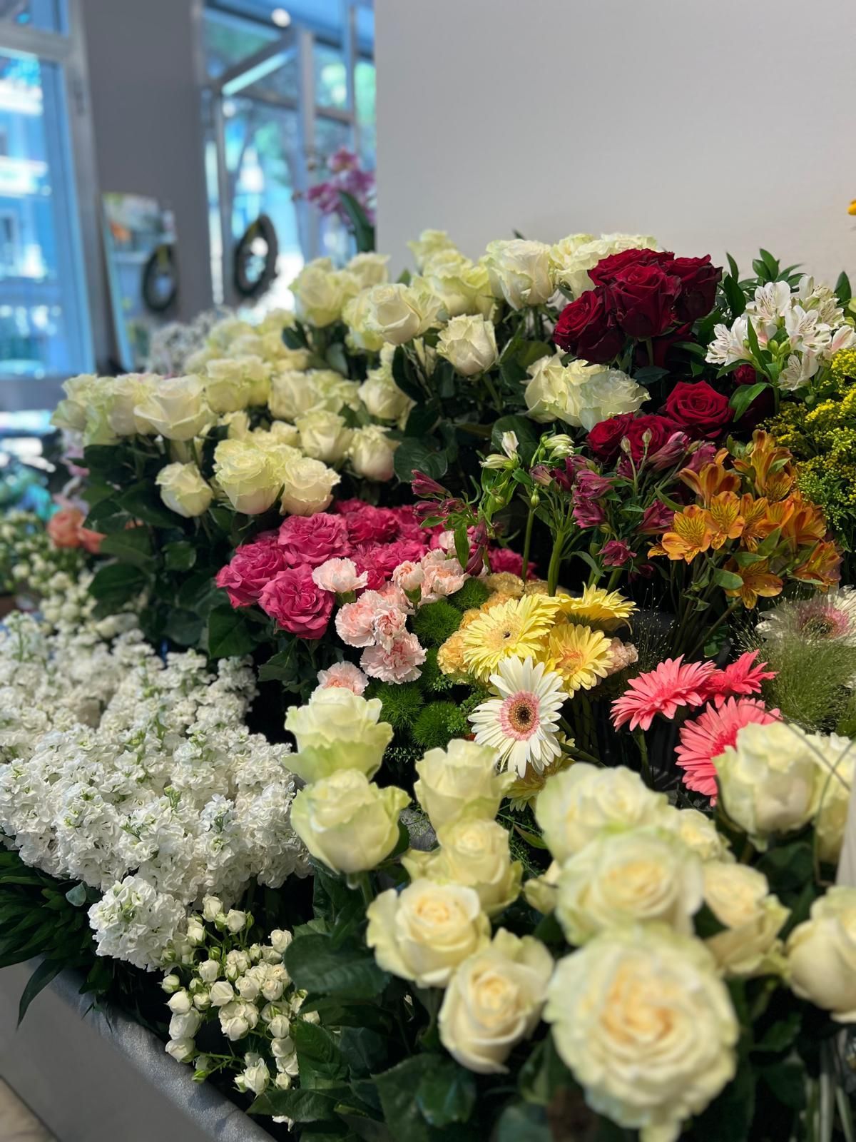 Un assortimento di fiori colorati disposti in un bouquet su un tavolo vicino a una finestra