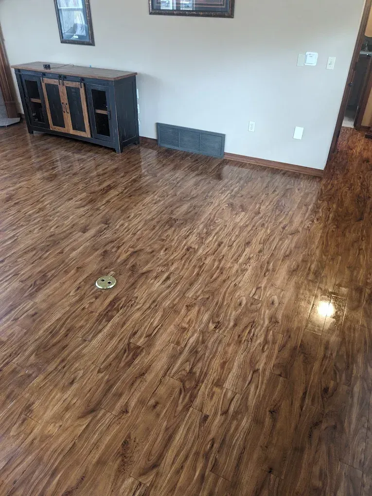 Empty room with glossy wood floor, white walls, and a dark TV stand along the back wall.