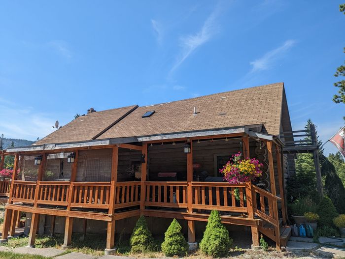 Rustic brown log cabin with stone chimney and yellow door under a bright blue sky