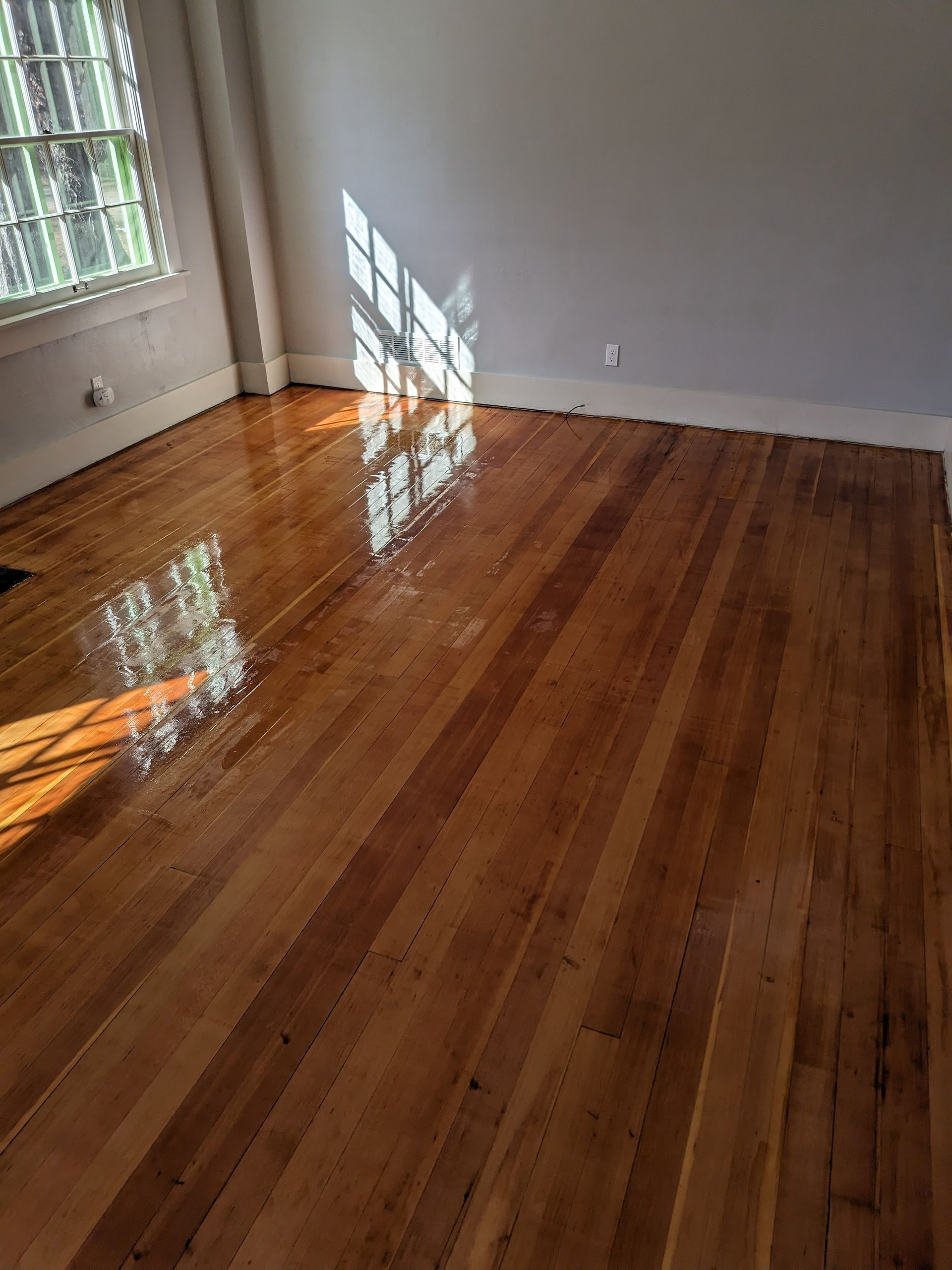 Worker installing wood-look floor tiles with adhesive spread on the subfloor
