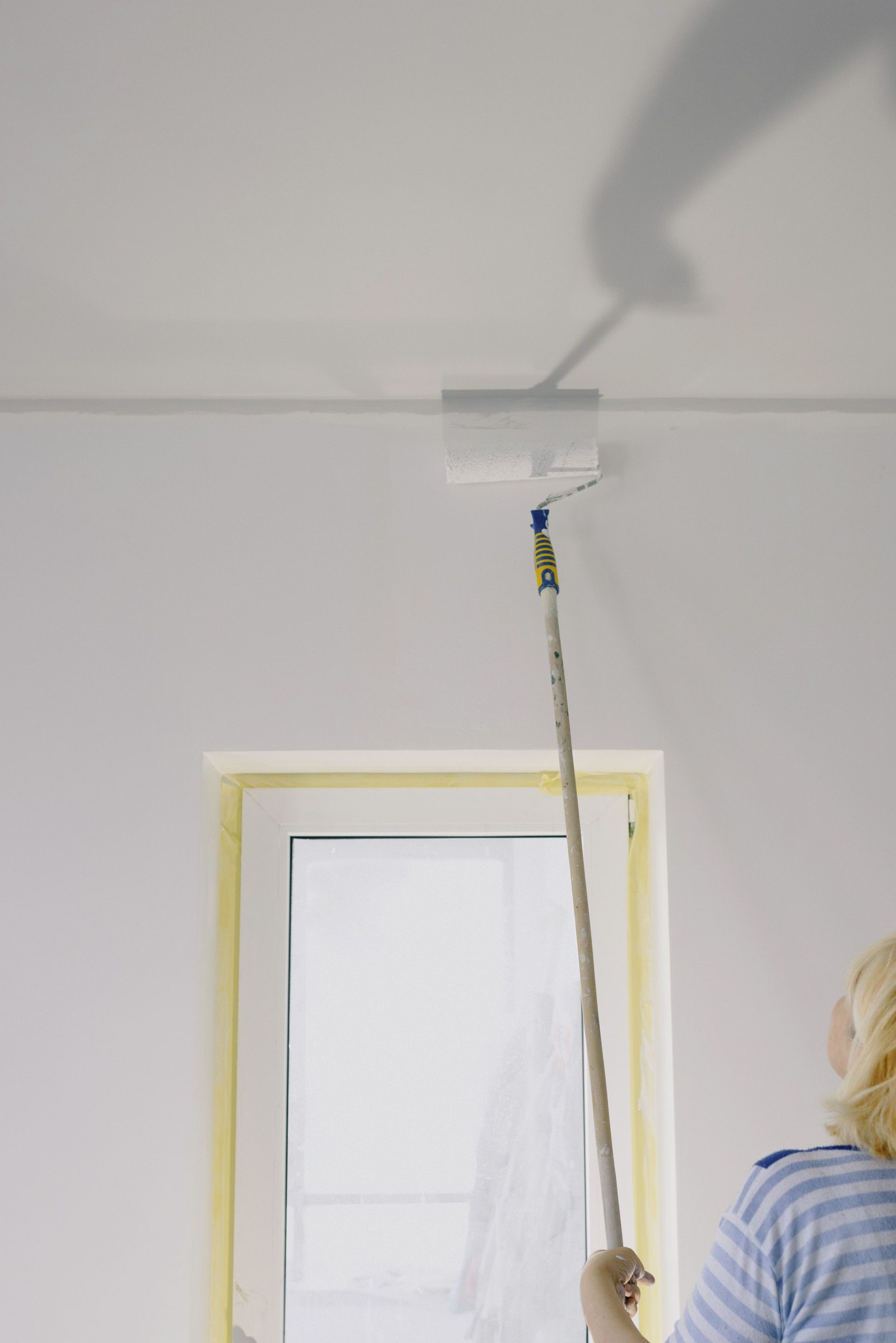 Hands installing beige siding around a white wall vent on a house exterior
