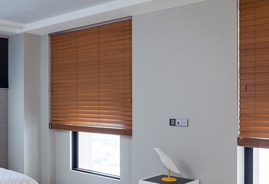 Bedroom with brown blinds covering two windows and a tissue box on a small table near the wall
