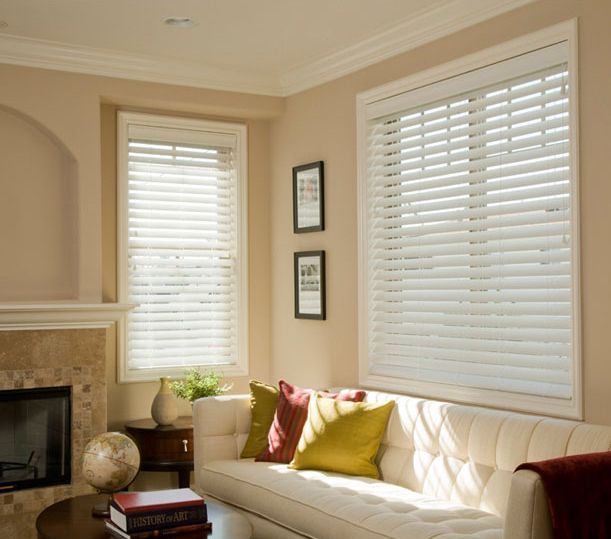 Bright living room with white blinds, cream sofa, red and yellow pillows, and a fireplace