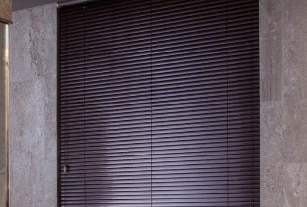Closed dark window blinds between two stone walls