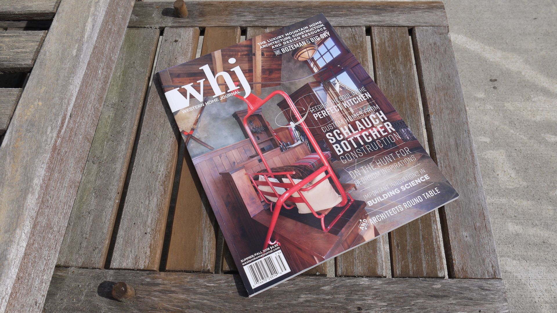 Magazine with “why” on the cover resting diagonally on a wooden outdoor table.