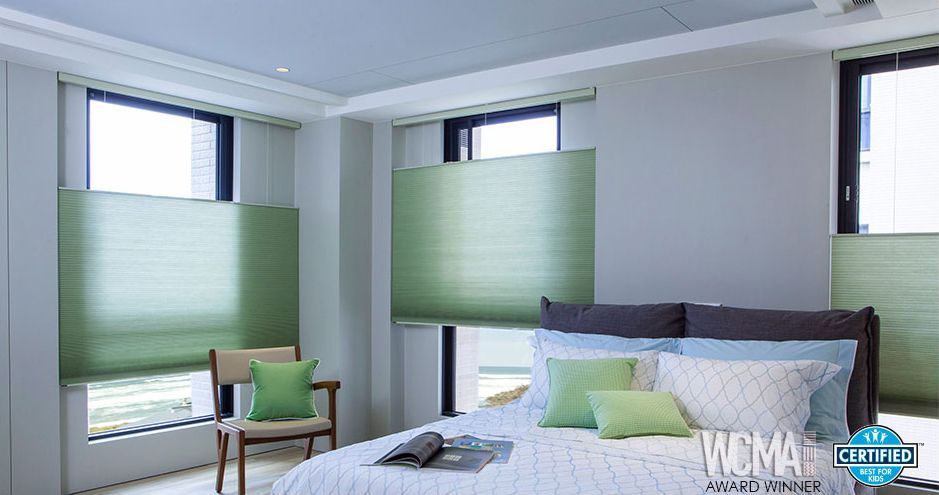 Bright bedroom with large windows, green blinds, and a bed with green and gray bedding
