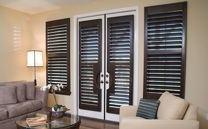 Living room with beige sofa, coffee table, and French doors with dark shutters